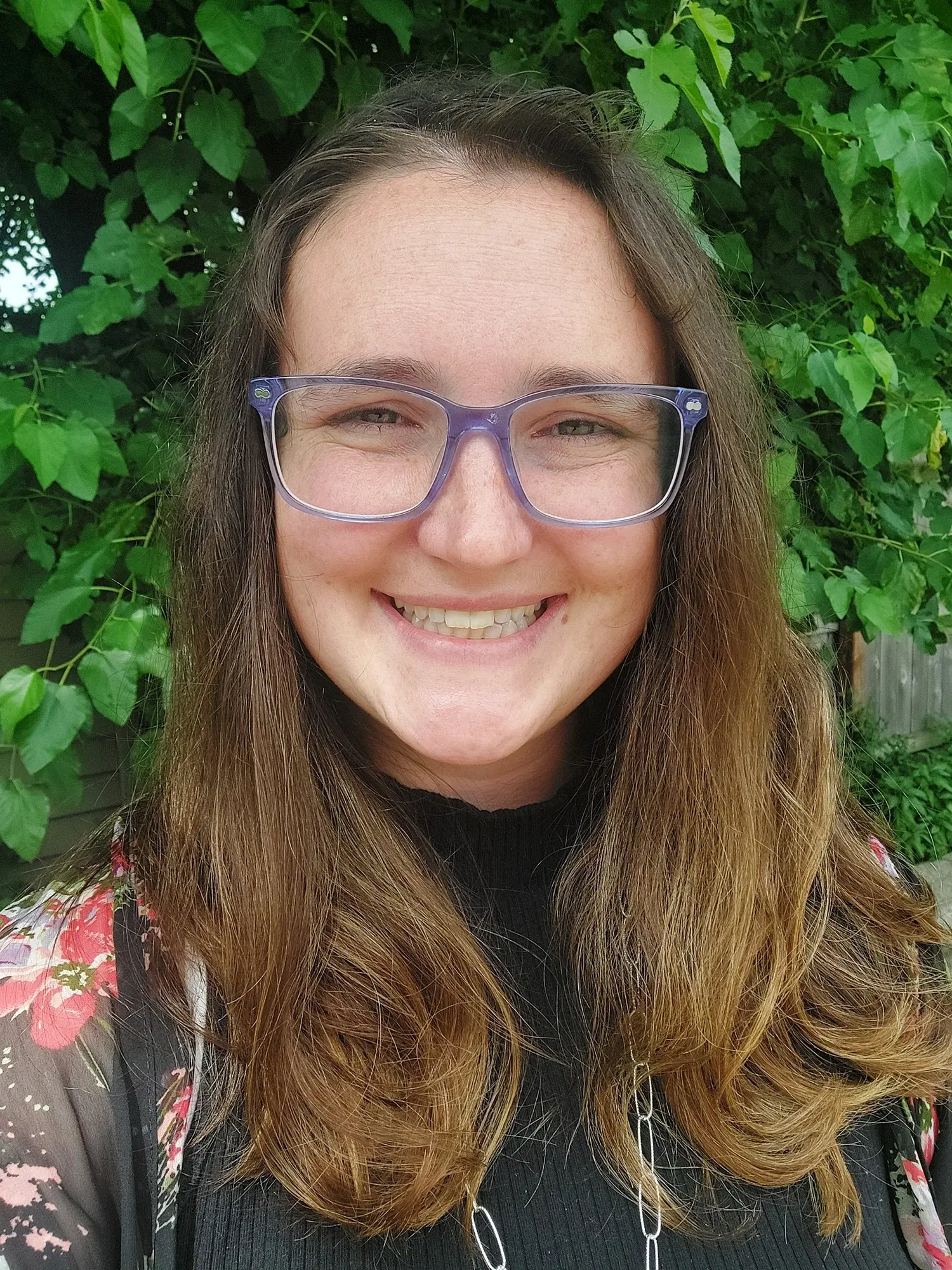 Dr. Cary standing in front of a tree smiling with glasses