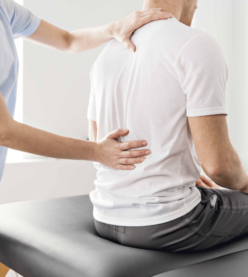 Person being evaluated by a physical therapist. Hands on their back and they are sitting